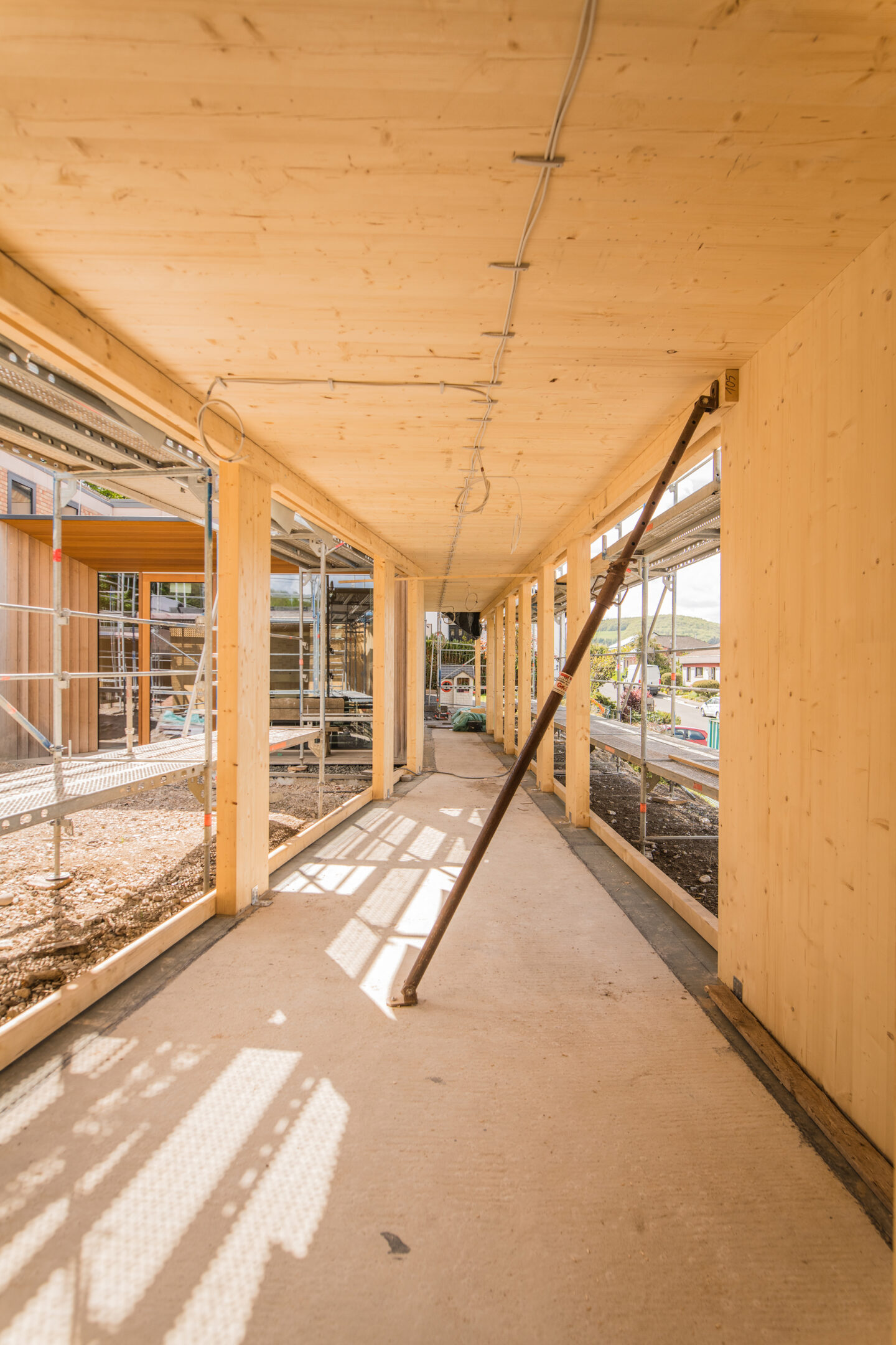 Zu sehen ist der Innenaus der Verbindung zwischen Neubau und Bestand. Der Innenausbau ist komplett in Holz gehalten und bietet viel Licht durch große Fensteröffnungen.